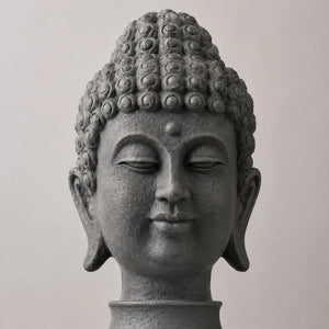 Gros plan sur le visage, les boucles sculptées et la finition gris sombre de la tête de Bouddha