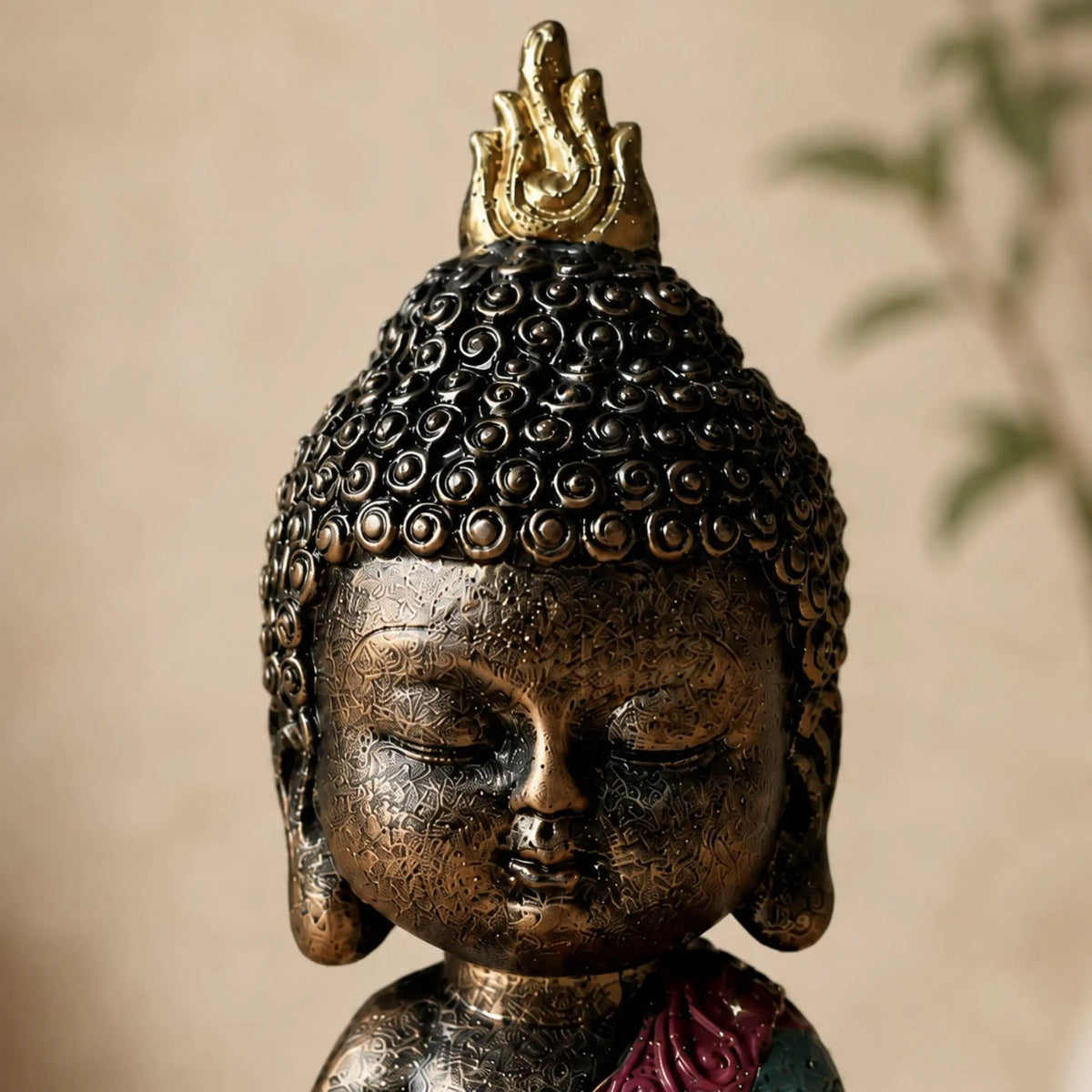 Gros plan sur le visage et la finition bronze de la statuette Bébé Bouddha en méditation