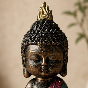 Gros plan sur le visage et la finition bronze de la statuette Bébé Bouddha en méditation