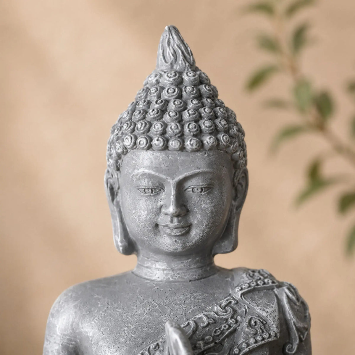 Gros plan sur le visage et la coiffure sculptée de la statuette Bouddha grise effet pierre
