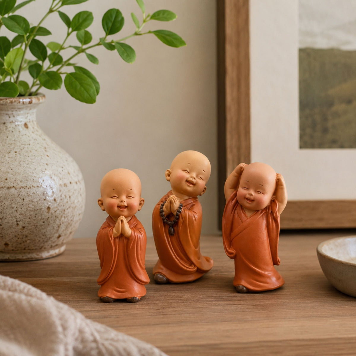 Trio de petits moines bouddhistes debout en décoration sur une étagère en bois